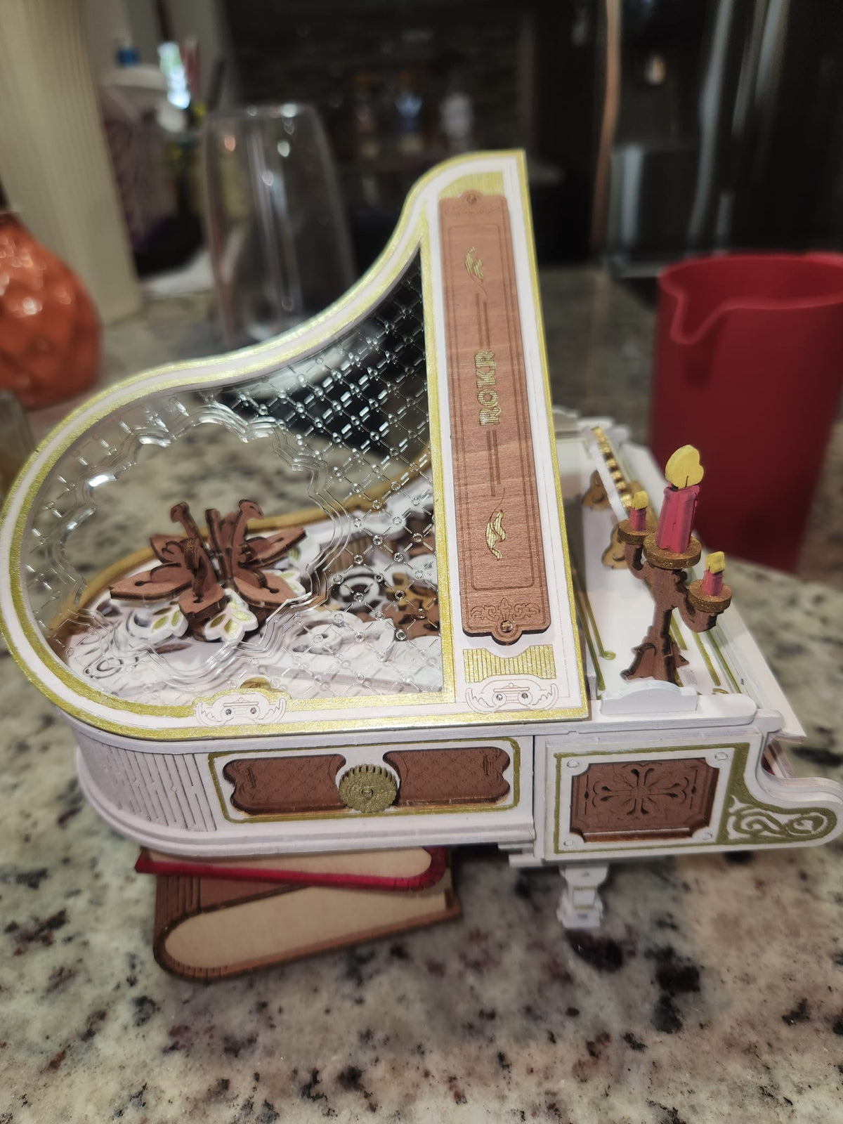 Robotime white grand piano music box has a raised lid and floral inlay on a tabletop.