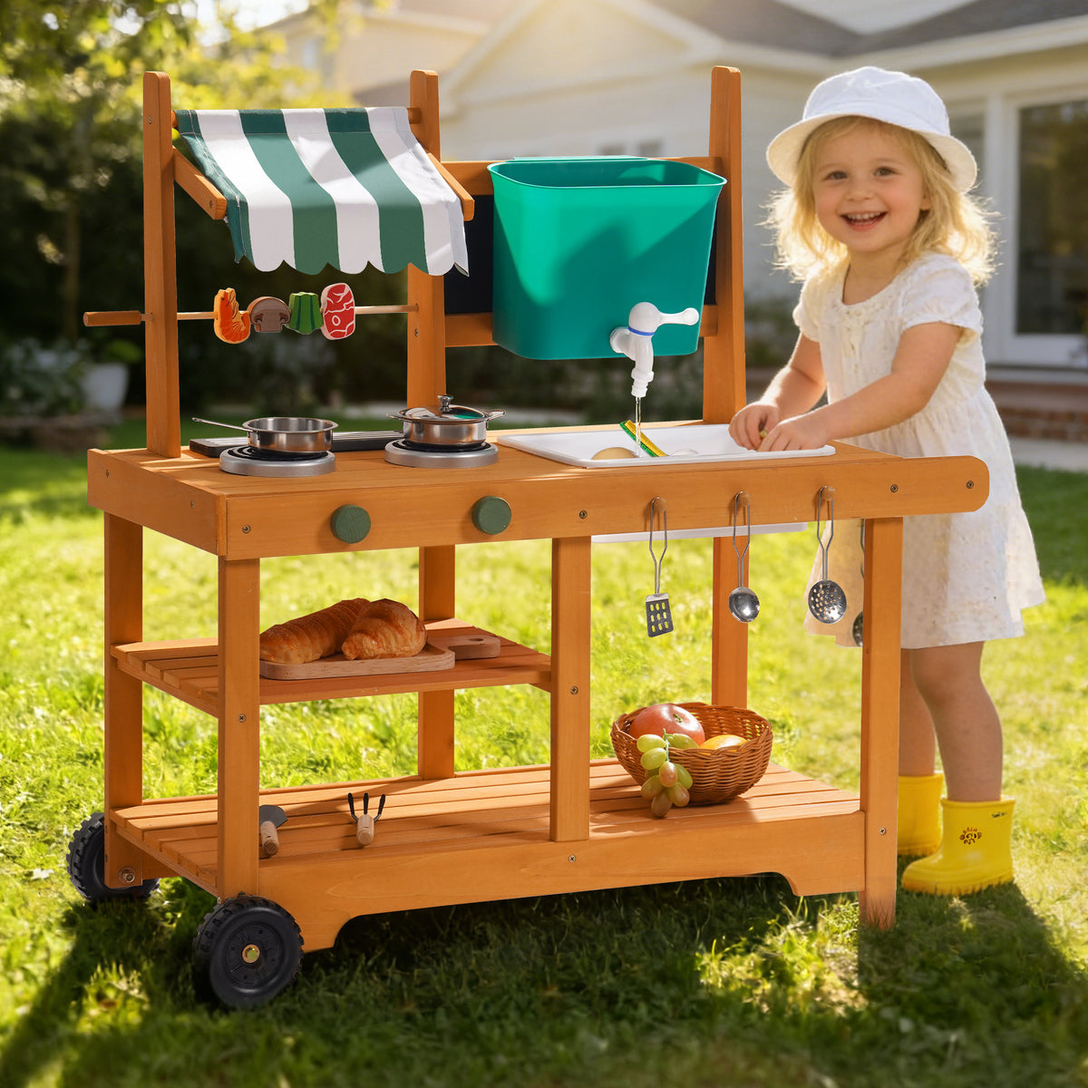 ROBUD wheeled outdoor mud kitchen displayed on a sunny lawn showing full natural wood structure with teal water bucket and green awning