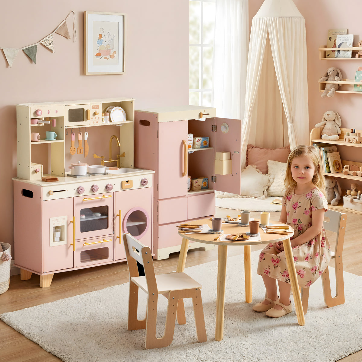 Child playing at a round wooden table with the full ROBUD Glowwood kitchen set and pink refrigerator displayed behind her.