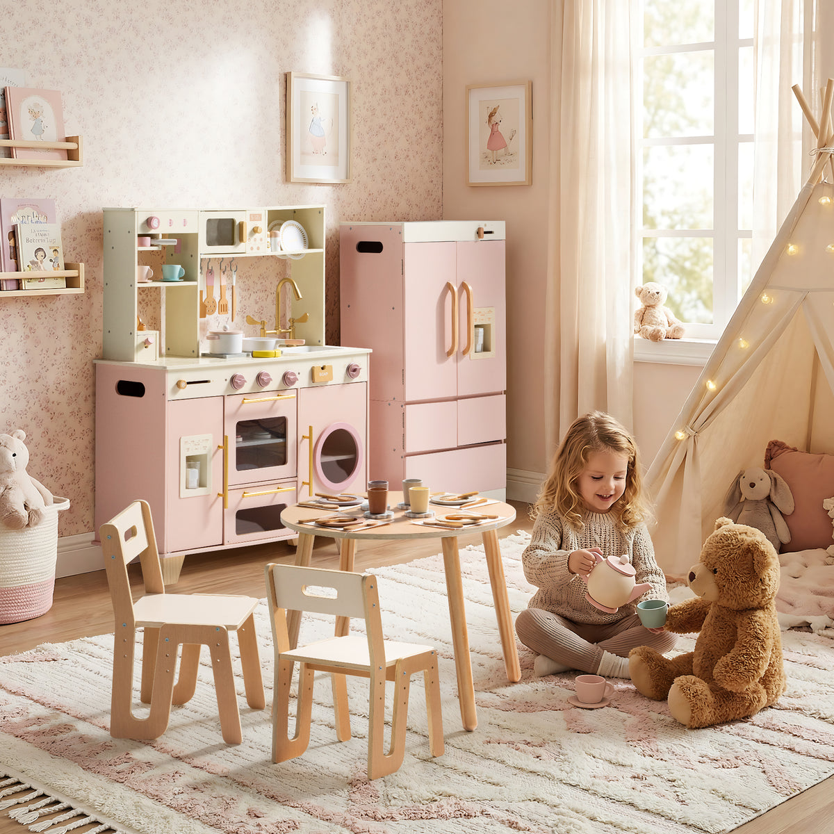 Little girl hugging a teddy bear at a natural wood table surrounded by the ROBUD Glowwood pink kitchen and fridge set.