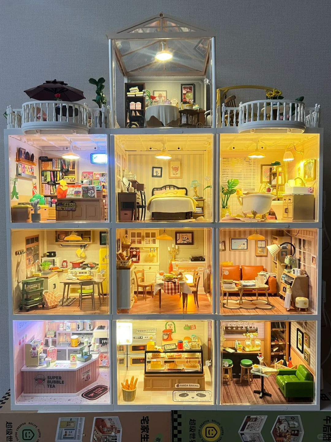 Illuminated Rolife multi-room dollhouse with five lit sections including bedroom, study, kitchen, and living room on display.