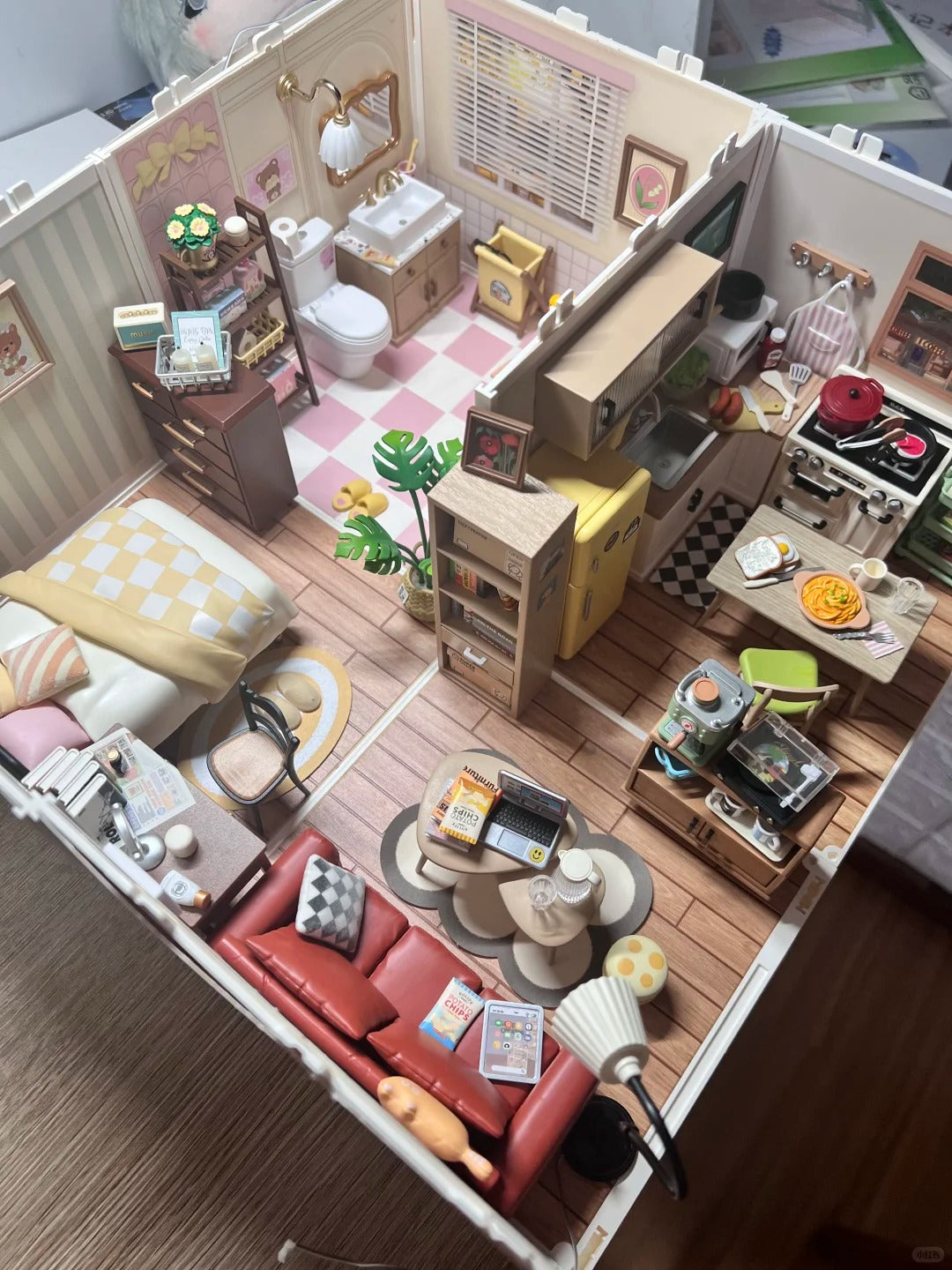 Rolife fairy tale dollhouse interior showing a pink bathroom and cozy kitchen with miniature furniture viewed from above.