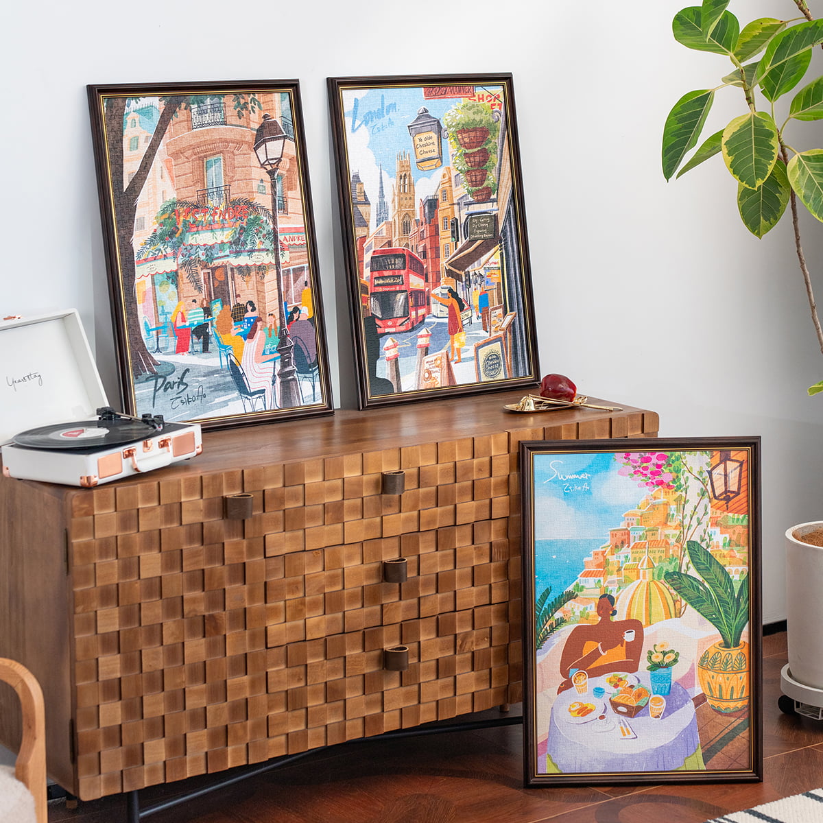 Three Rolife jigsaw puzzle framed prints displayed on wooden sideboard showing colorful illustrated city street scenes