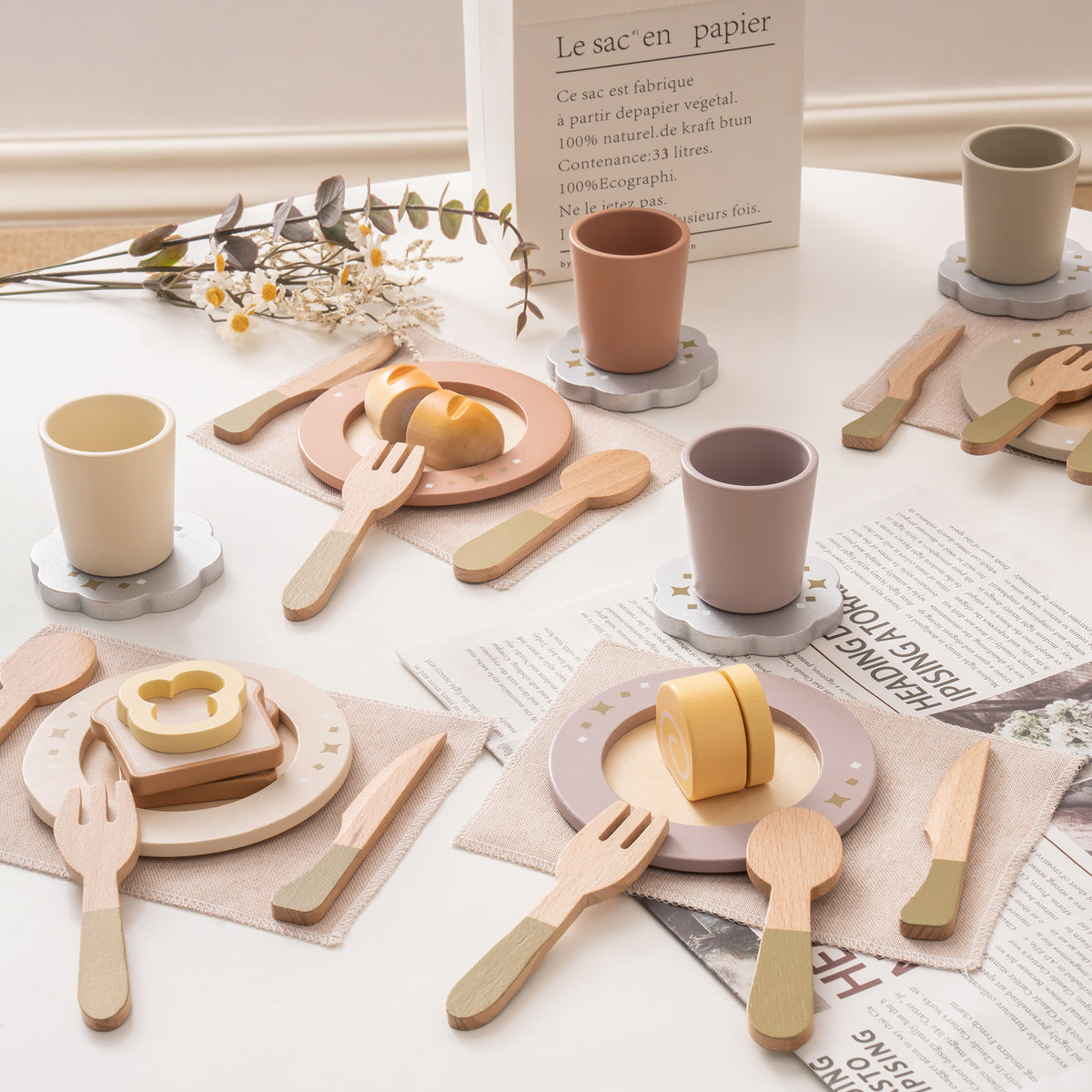 ROBUD Glowwood wooden play kitchen accessories laid out on a table including plates, cups, and utensils in neutral tones.