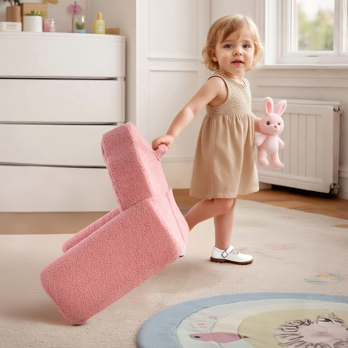 Toddler girl dragging the ROBUD pink Children's Sofa cushion while holding a stuffed rabbit in a playroom
