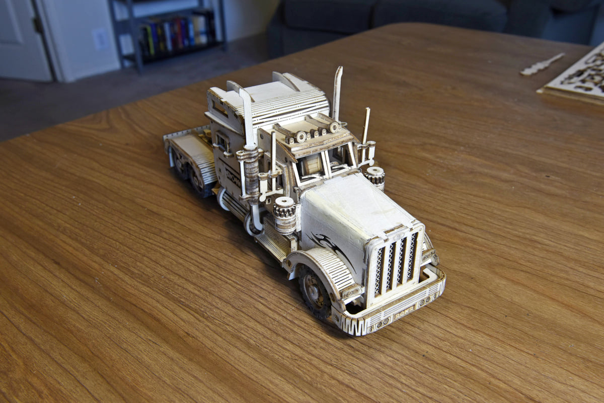 Robotime white truck model shows a detailed grille and cab on a wooden table.