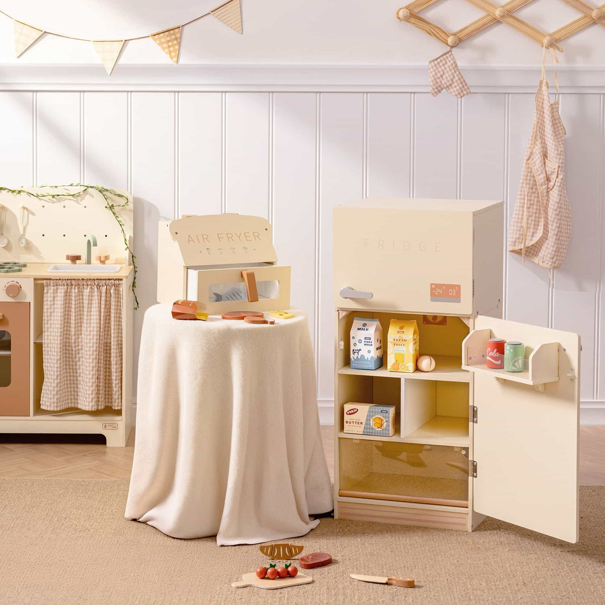 ROBUD creamy wooden play fridge and toy air fryer staged together in a play room setting, fridge open showing milk cartons and interior shelves