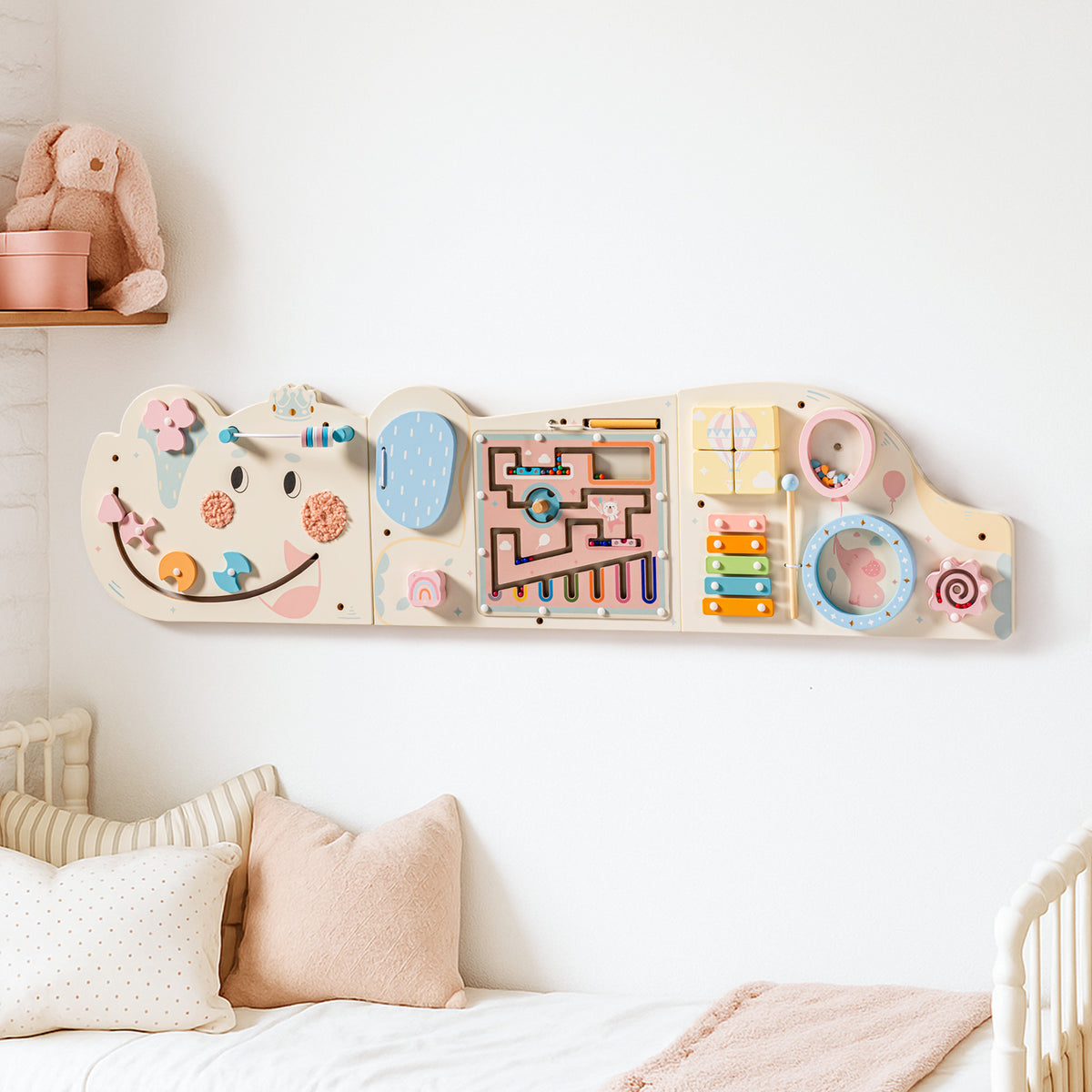 ROBUD wooden activity board mounted on a white nursery wall above a cot showing colourful sensory panels for toddlers.