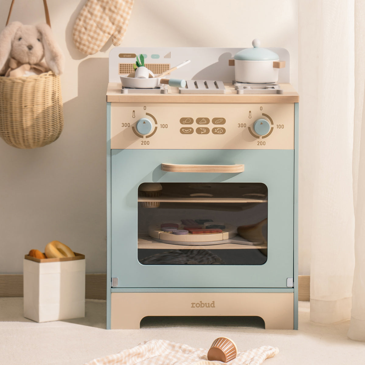 Robud mint blue wooden play oven with glass-front door and gold knobs styled in a warm bedroom setting