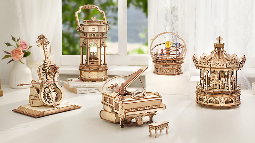 Rolife wooden music box collection with violin, carousel, lantern, grand piano, and globe models on a white table