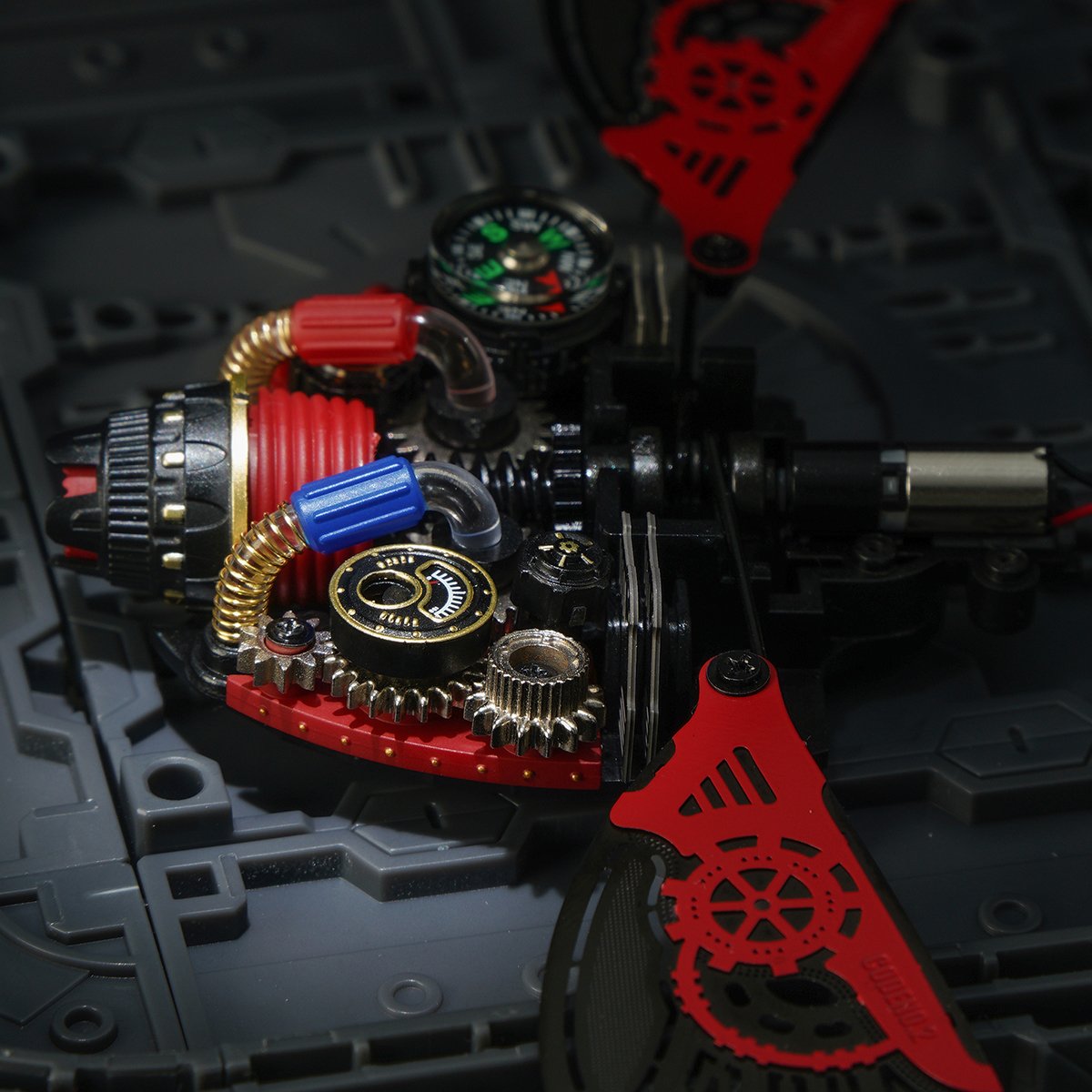 ROKR Scout Beetle mechanical puzzle close-up revealing brass gears, a compass, and vivid red filigree wing frames