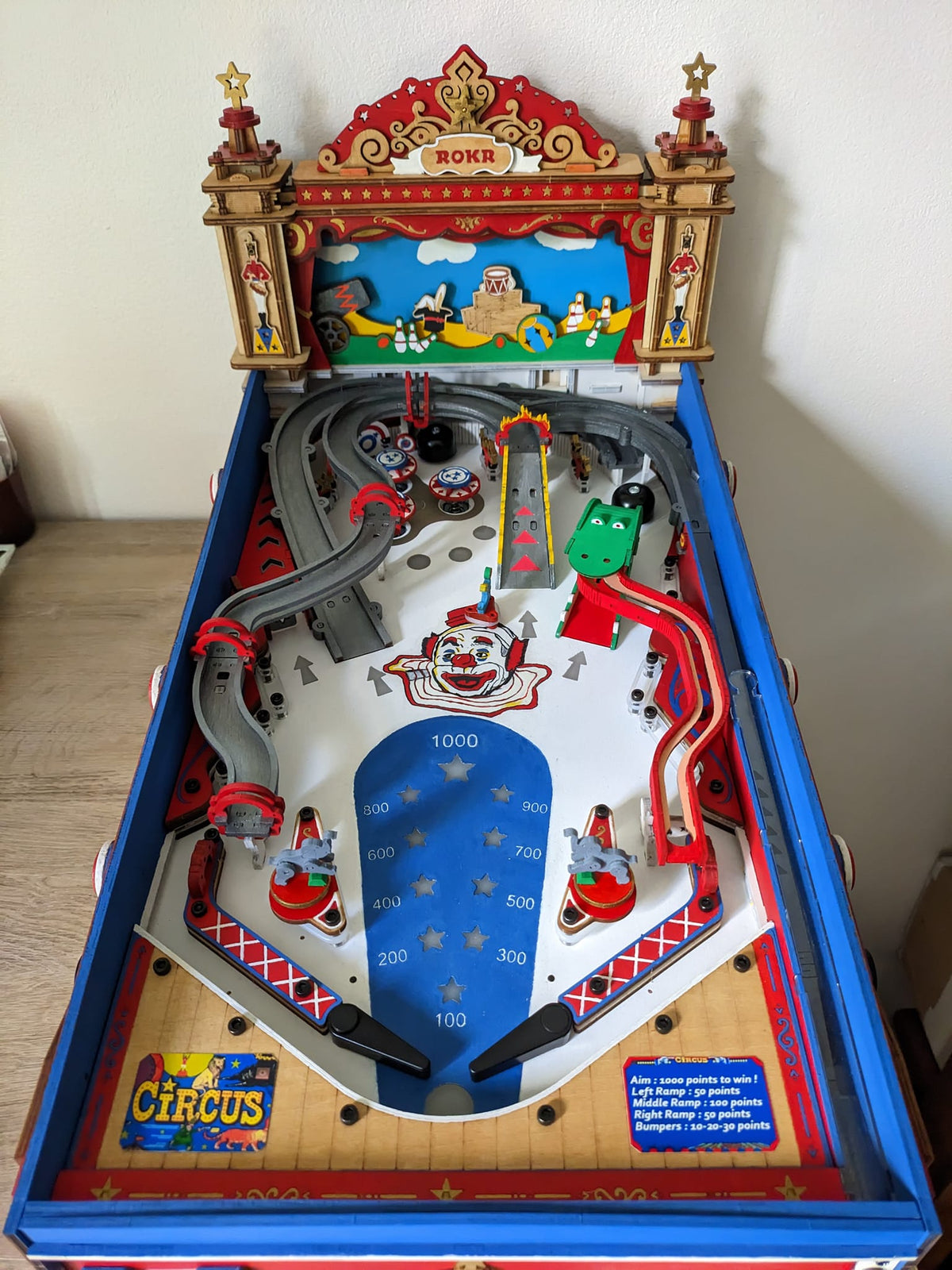 Robotime circus pinball table has a blue launcher, red rails, and colorful backboard.