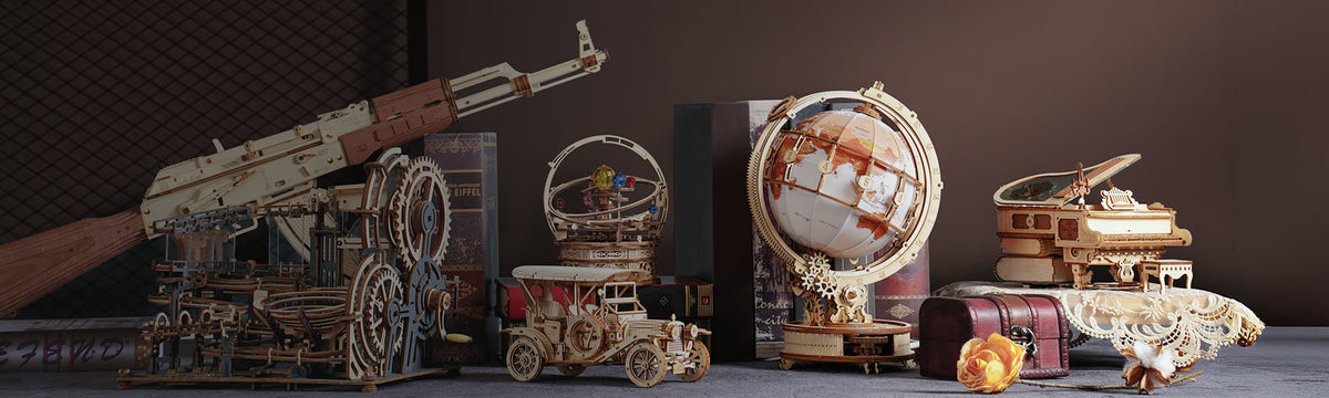 ROKR wooden model collection flat-lay showcasing a machine gun, orrery, vintage car, globe and piano music box on a studio surface.
