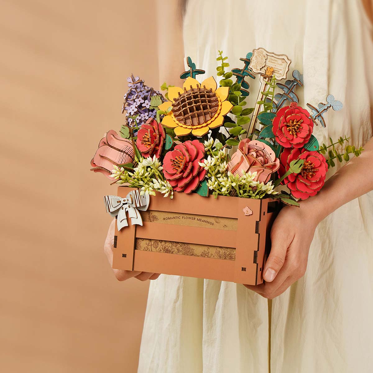 Person in white dress holding Rowood Wooden Bloom Box with sunflower and rose arrangement outdoors