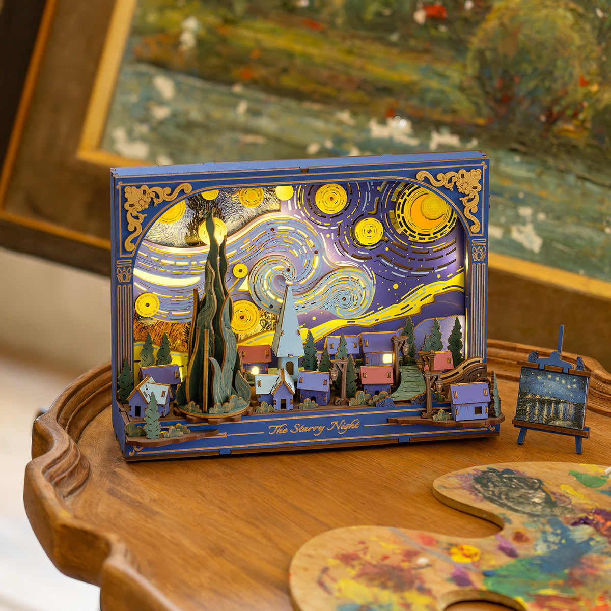 Rowood The Starry Night Wall Art 3D Wooden Puzzle TH003 lit lifestyle, the illuminated blue Van Gogh scene displayed on a round wooden tray table with a mini painted easel beside it