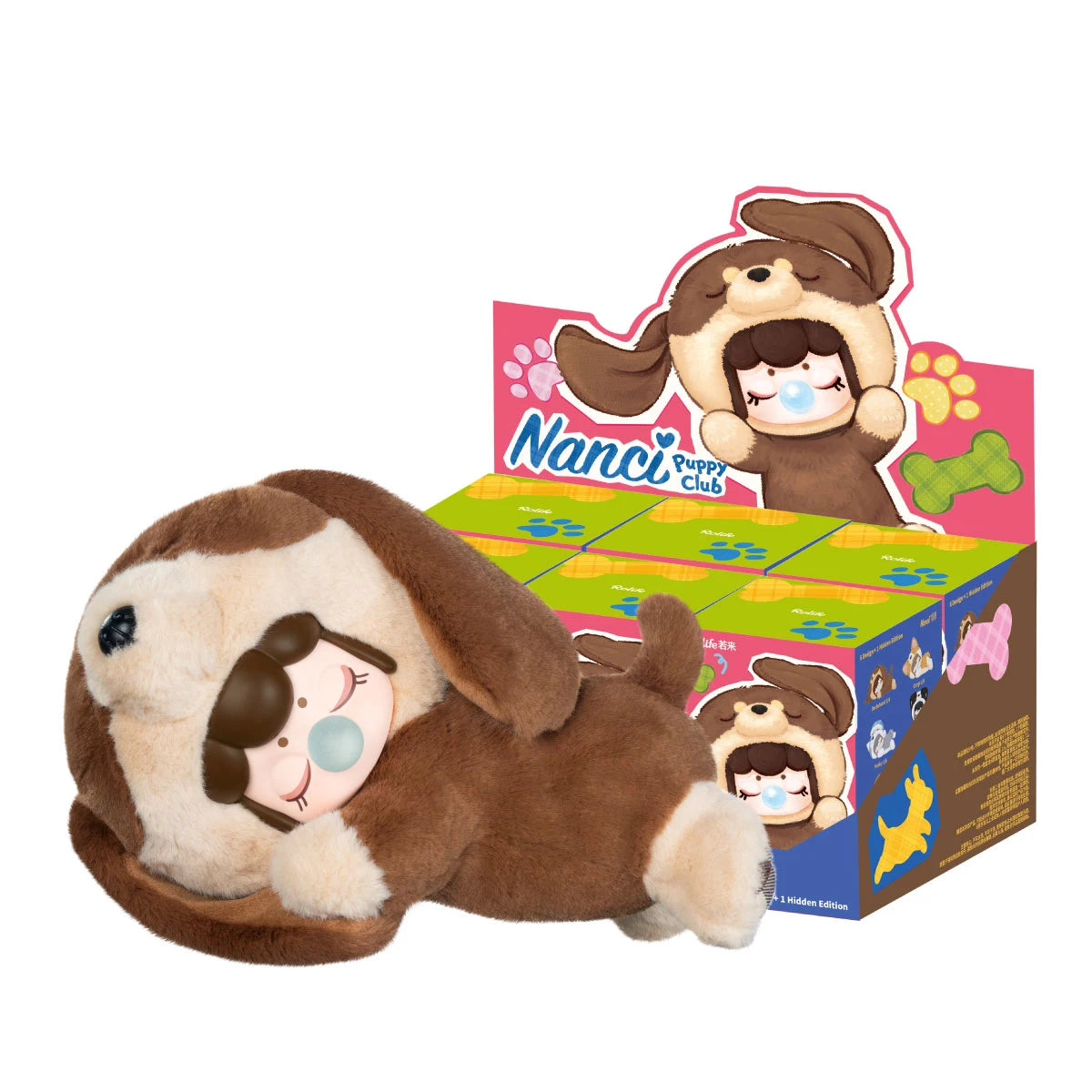 Plush brown puppy-hooded figure lying on its side with closed eyes and blue bubble, beside a Rolife Nanci Puppy Club display case.
