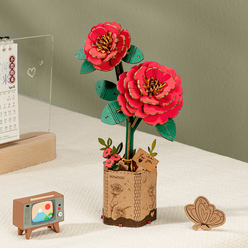 Rowood wooden red flower pair stands in a paper bag style planter on a shelf.