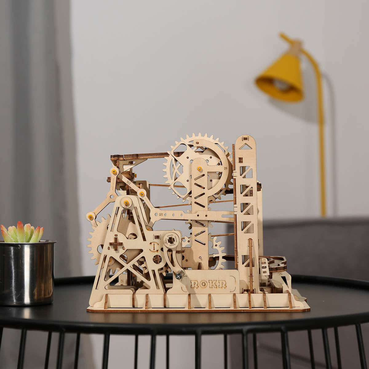 ROKR Marble Climber Fortress LG504 assembled in natural birch wood on dark table with yellow lamp behind