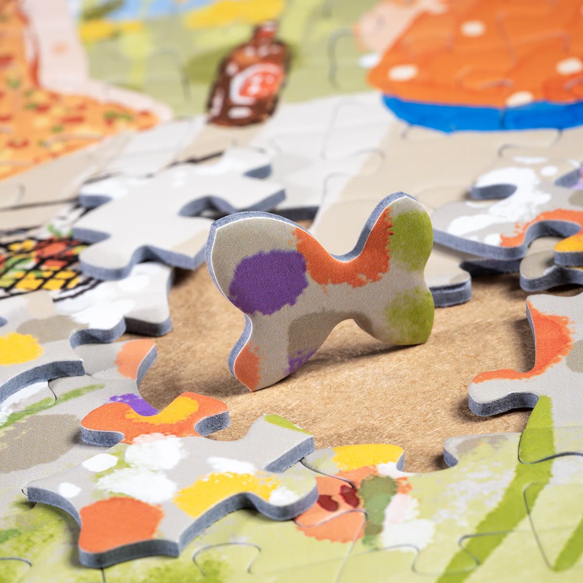 Close-up of Rolife Afternoon Fountain PT001 puzzle piece lying on spread showing illustrated soft green and orange garden tones