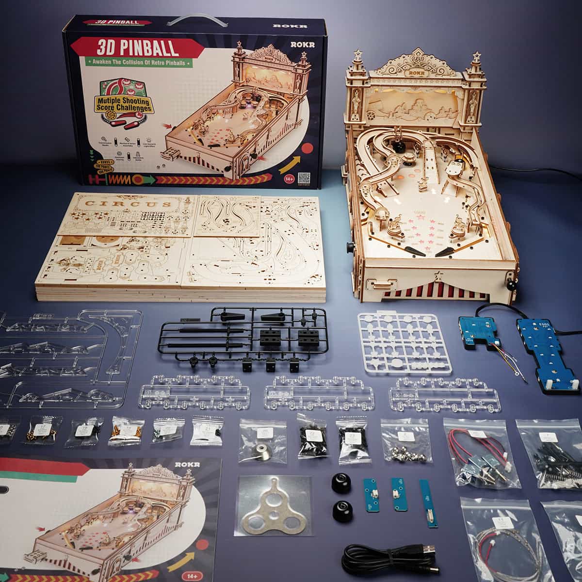 ROKR 3D Pinball Machine puzzle flat lay with box, laser-cut wooden sheets and LED components spread on dark surface