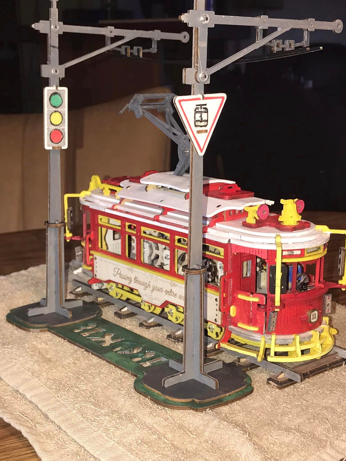 Robotime tram model stands on tracks beneath street signs and overhead wires.