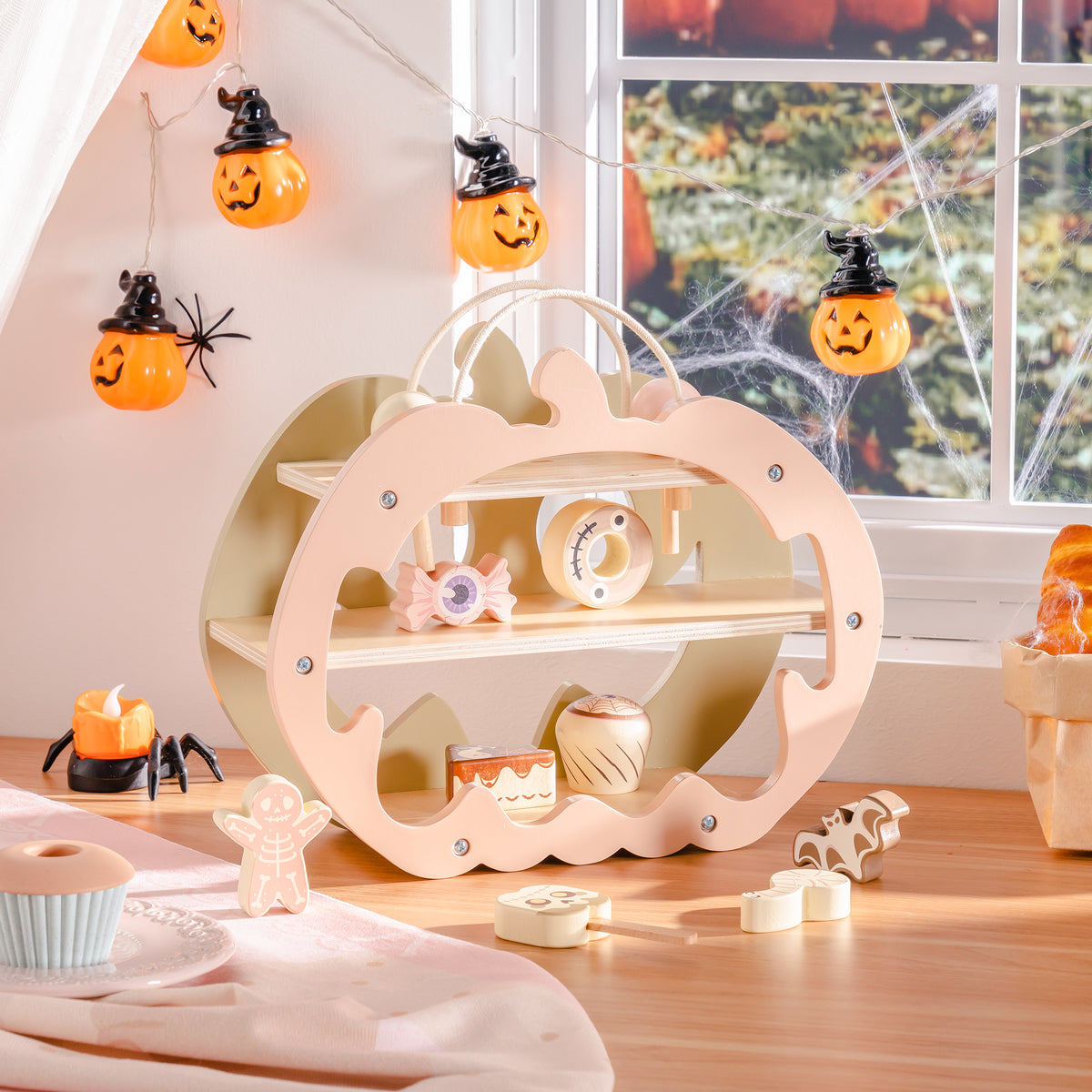 ROBUD Halloween Candy House pumpkin playset front view showing jack-o-lantern face cutouts and cream-painted wood on spider-decorated windowsill