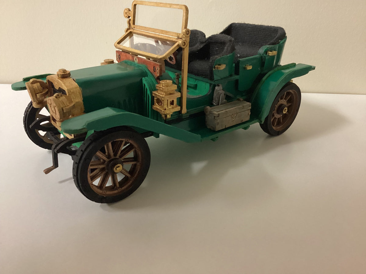 Robotime green vintage car model has tan seats and black wheels on a plain surface.