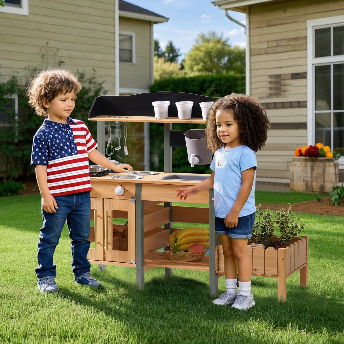 Two children playing outdoors with the ROBUD wooden mud kitchen in a garden setting, using stainless steel pots and the working faucet at the natural wood counter