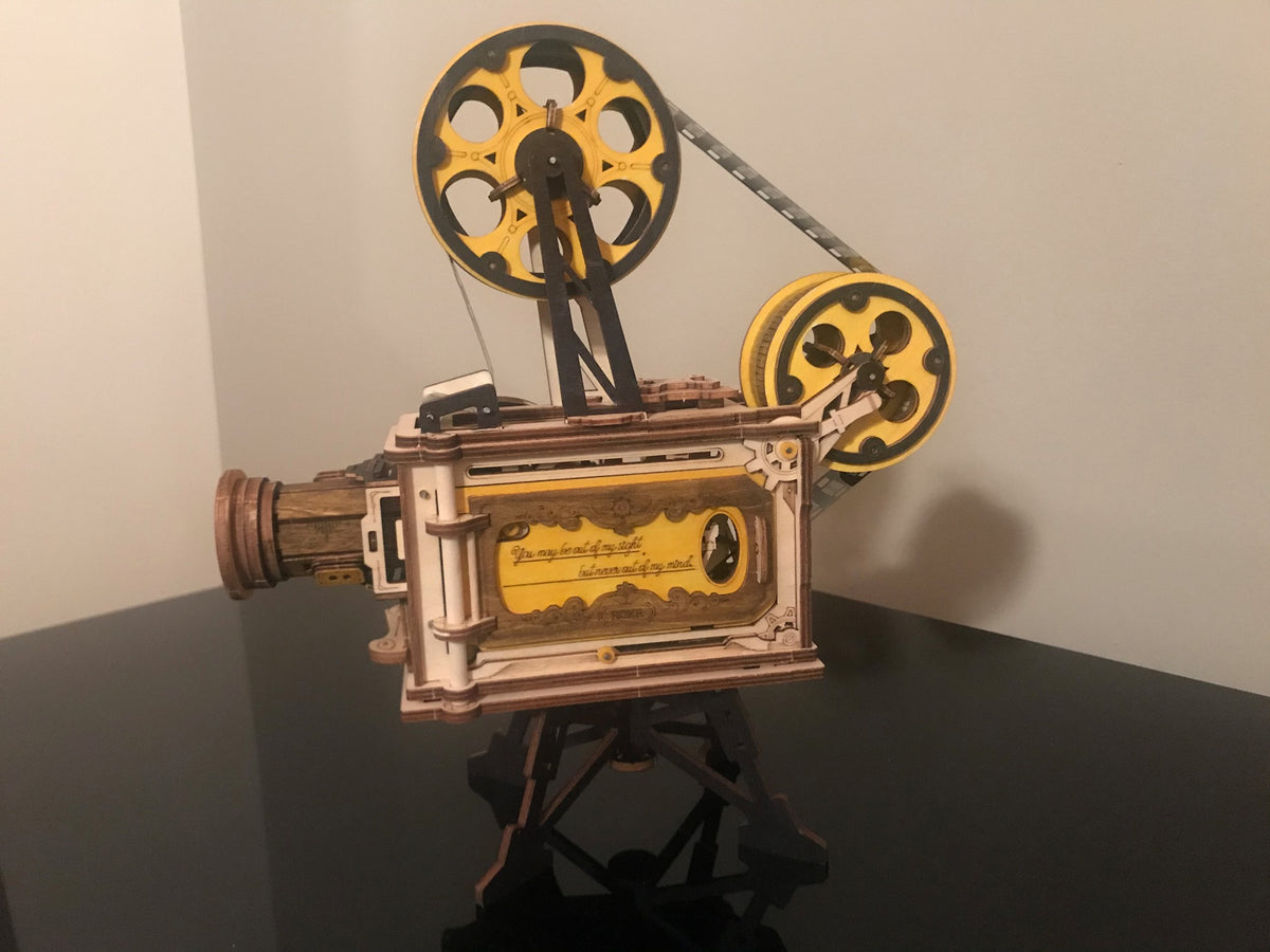 Robotime film projector music box stands on a black base with gold reels.