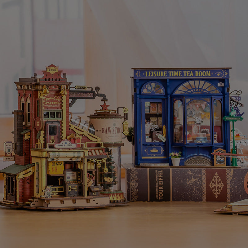 Robotime Dream City Factory steampunk miniature and Leisure Time Tea Room miniature house displayed side by side on a desk in a warm room