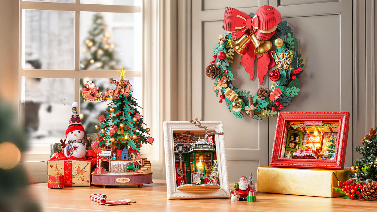 Rolife Christmas Wreath TGL04 on a shelf beside a rotating Christmas tree and illuminated book nook with fireplace