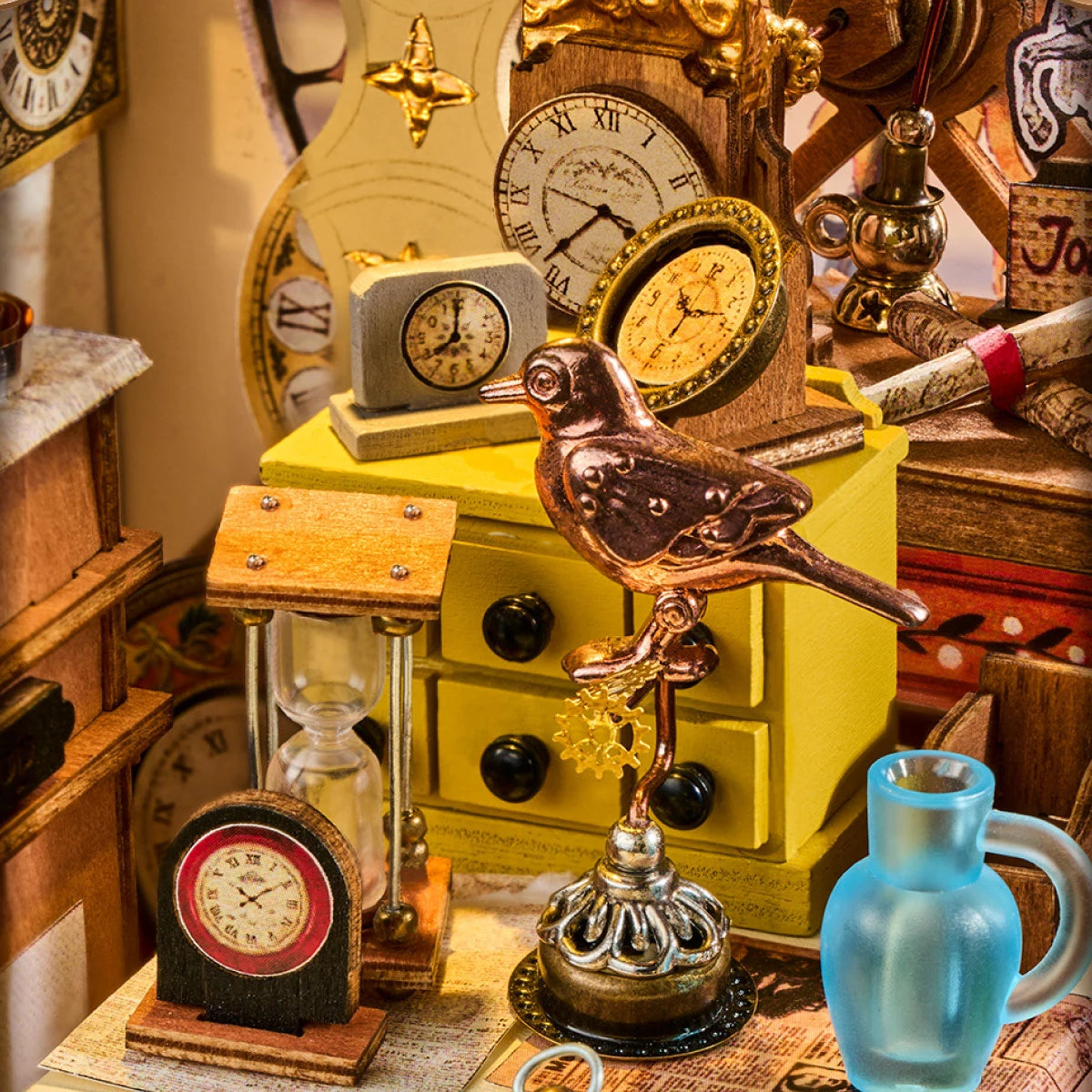 Miniature clockmaker's workshop scene with a copper bird figure on a gear stand, yellow drawers, hourglass, small clocks, brass oil lamp and blue glass jug.