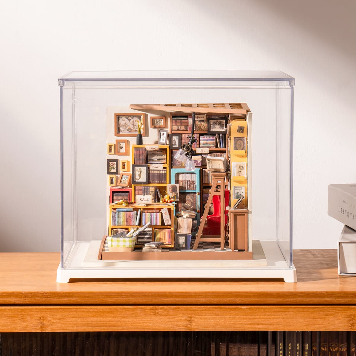 Rolife Sam's Study Library sits inside a clear display box on a wooden tabletop.