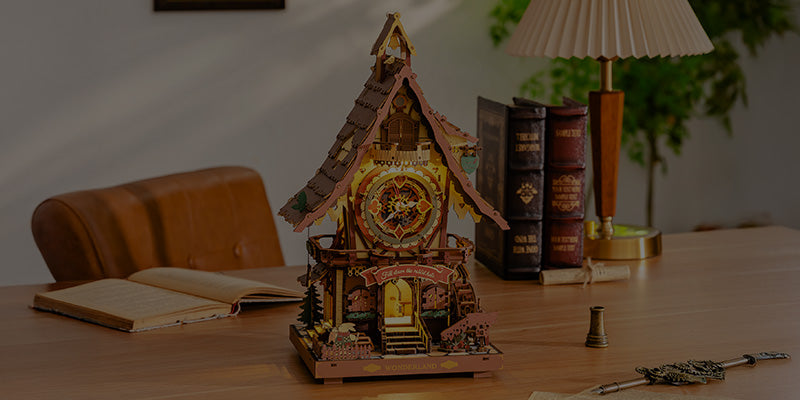ROKR Wonderland cuckoo clock wooden puzzle glowing on a desk beside books, candle and vintage key, representing Robotime desk decor collection