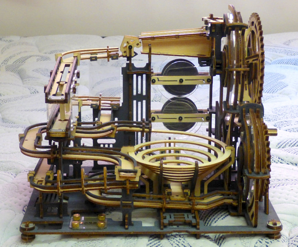 Fan-built ROKR marble run 3D wooden puzzle assembled on a white surface showing golden-toned tracks, large gear wheel and dual glass marble chambers