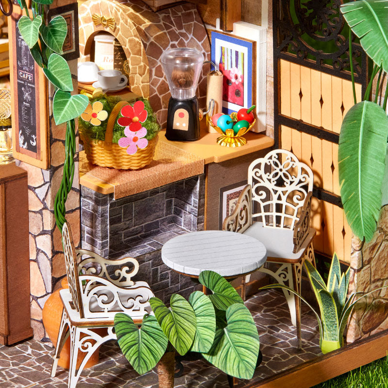Leafree Cafe patio detail with white metal furniture, potted plants and a stone wall