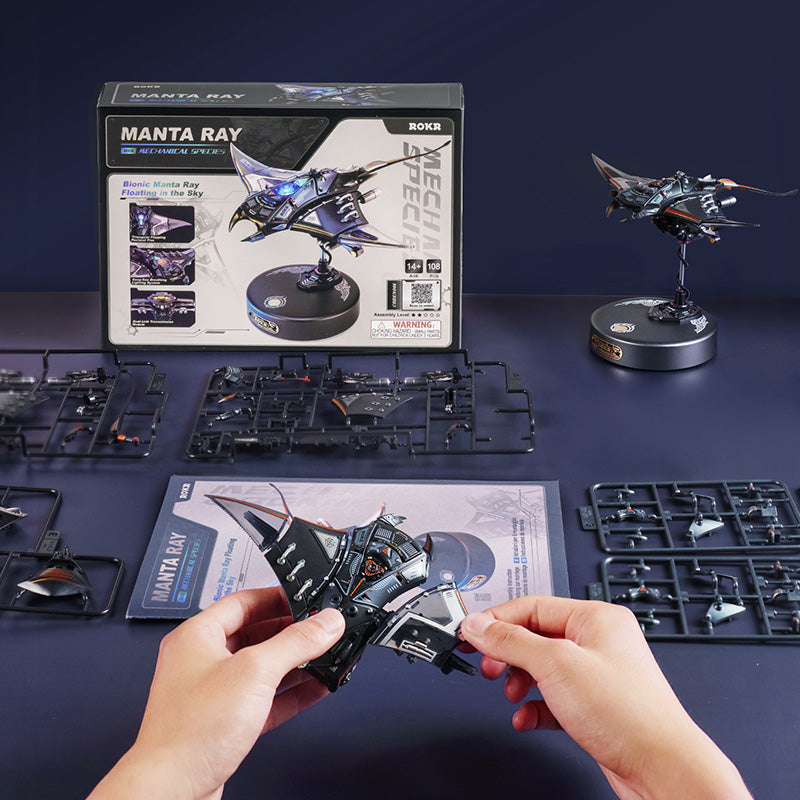 ROKR Manta Ray MI06 kit view, ROKR box with sprues, instruction sheet, and partially built manta ray model on a dark navy surface