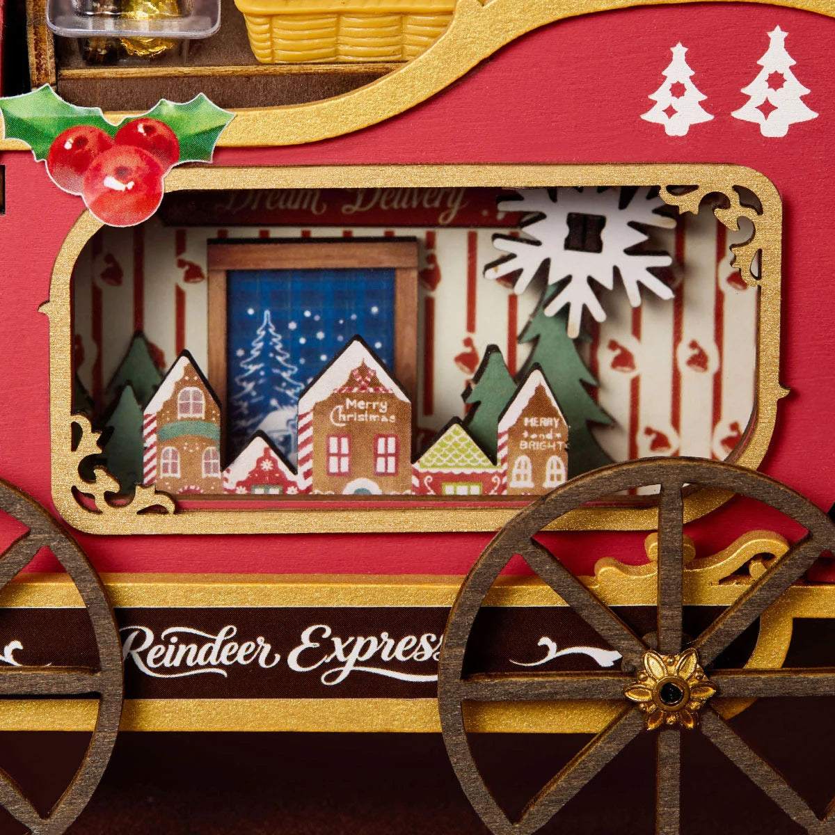 Close-up of a red sleigh side panel with gold trim, holly, a window showing a miniature village scene, and the text Reindeer Express.