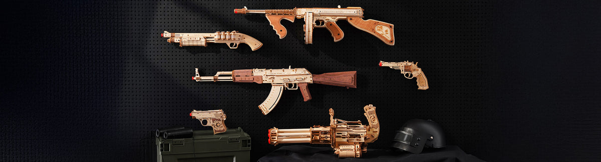 ROKR Justice Guard rubber-band gun collection on a dark pegboard wall featuring six wooden weapon replica models including an AK-47, tommy gun, Gatling cannon, pistol, shotgun, and revolver