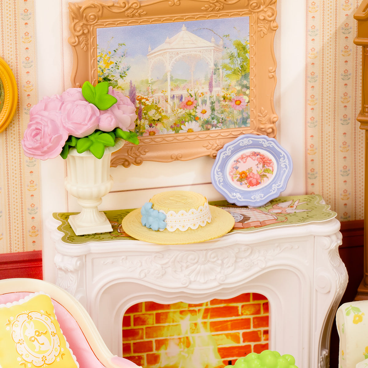 Rolife Holiday Tea Time DW023 fireplace mantel close-up showing a pink rose vase and a yellow straw hat beside a floral painting above the brick firebox