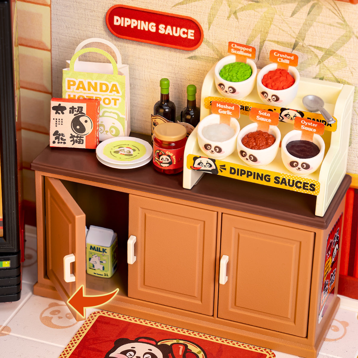 Close-up of the Rolife Panda Hot Pot DW020 dipping sauce station showing six condiment bowls labeled garlic, salsa, oyster sauce, scallions, and chili on a brown cabinet with open door
