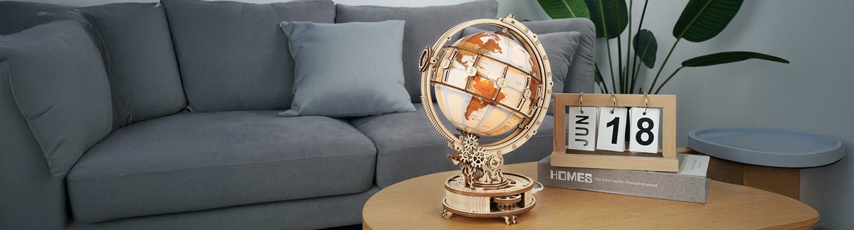 ROKR Luminous Globe ST003 lifestyle banner, glowing amber wooden world globe with gear base displayed on a coffee table beside a sofa