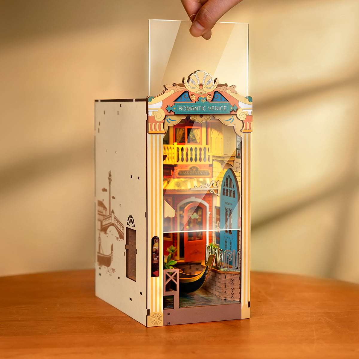 Rolife Romantic Venice TGB08 Book Nook displayed on desk beside books and candle holder showing daylight view of the colorful canal diorama