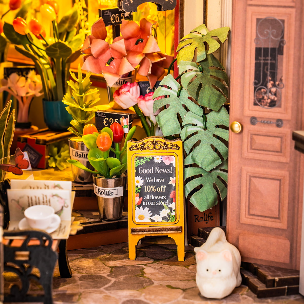 Rolife Floral Corner TGB09 Book Nook close up of flower shop entrance with tulips monstera leaves sandwich board sign and white cat figurine
