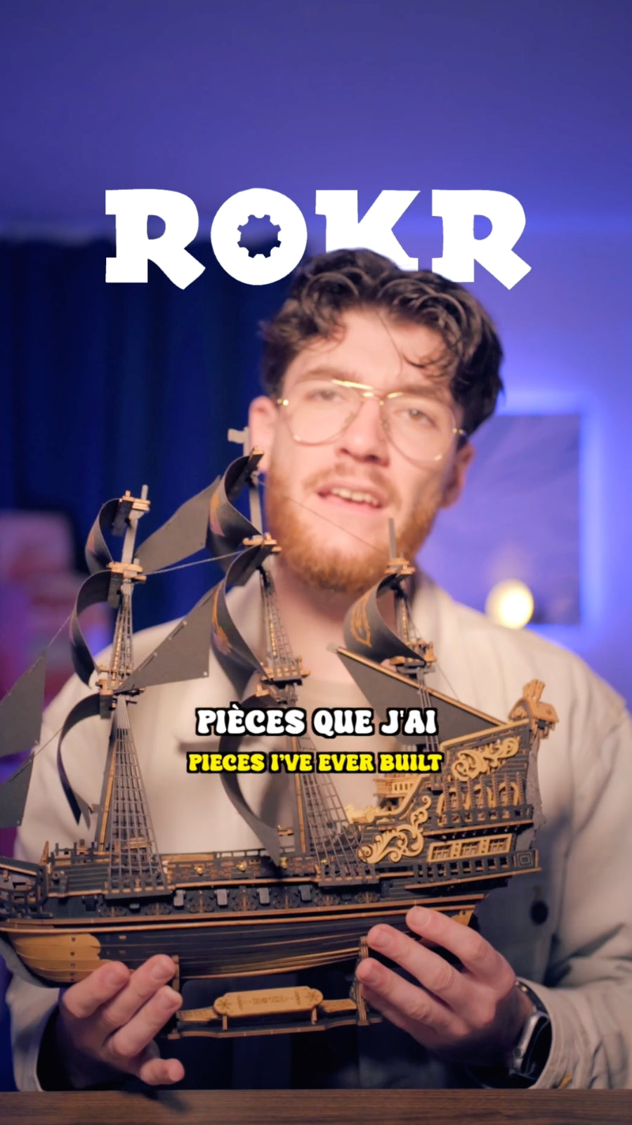 Man holding a wooden mechanical revolver model beneath a bold white ROKR logo