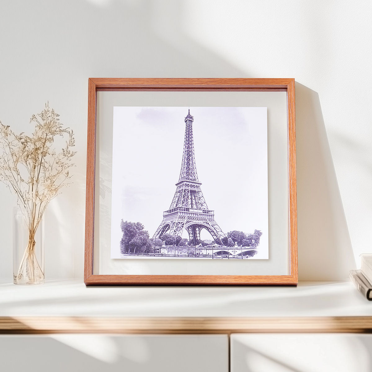 Robotime Double Glass Picture Frame WD6001 close-up product shot showing the warm oak-finish square frame with Eiffel Tower print resting on a white sideboard