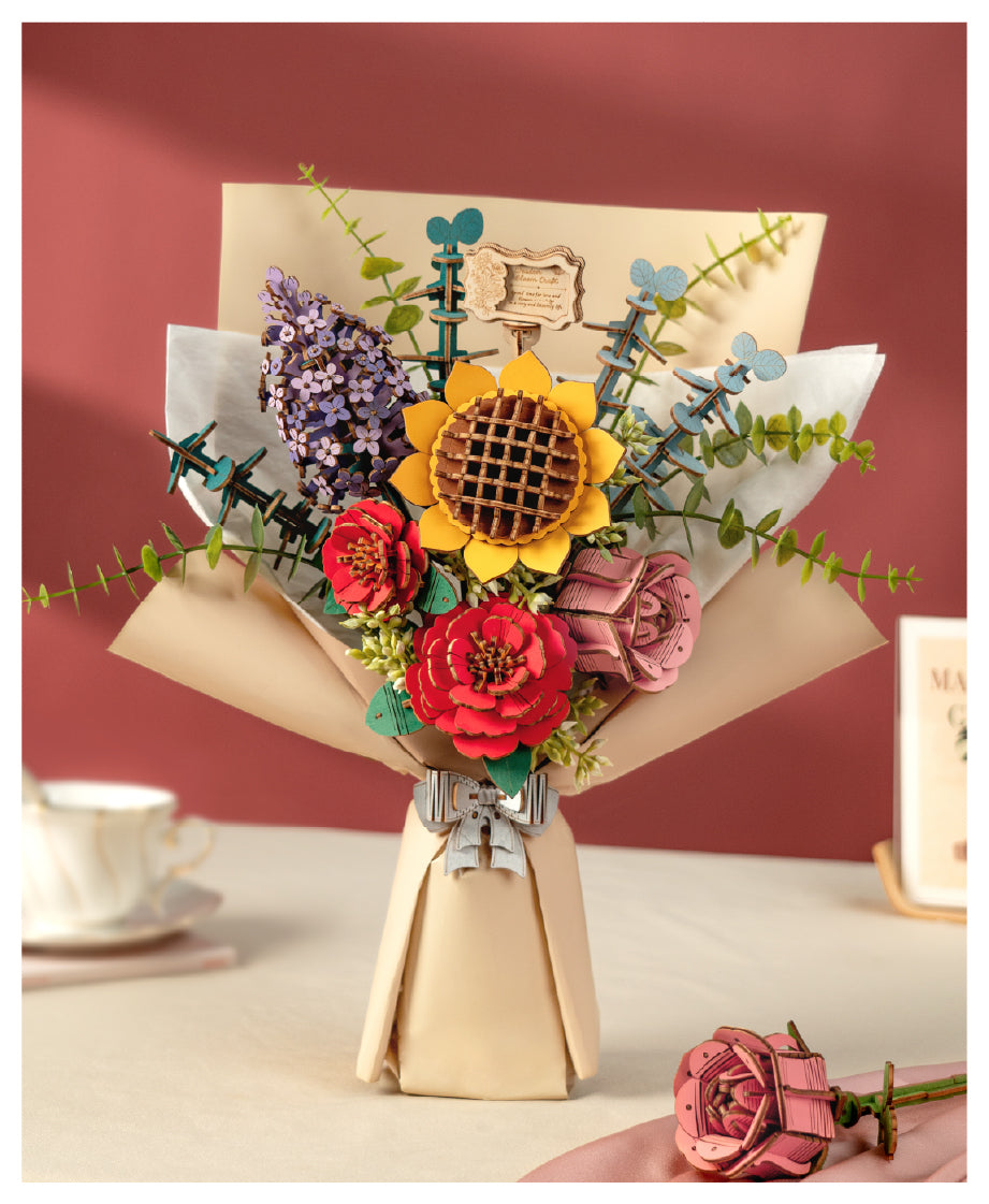Rowood wooden flower bouquet kit with a sunflower, red roses and lavender sprigs wrapped in kraft paper on a table.
