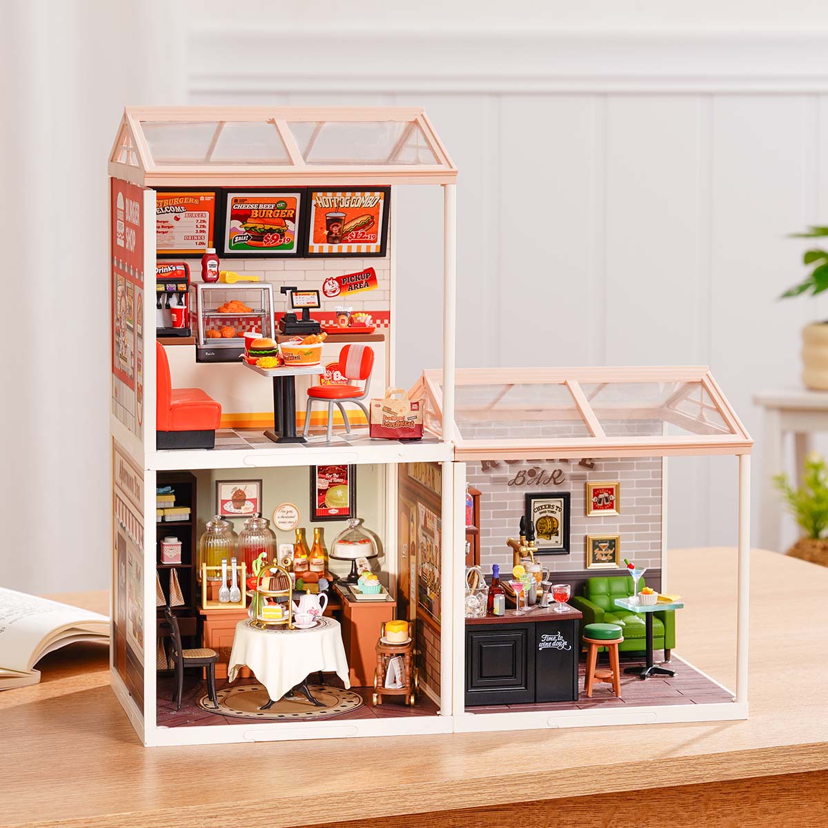 Rolife Super Creator Series 3-in-1 L Shape miniature combining cake bakery and ice cream shop on top with a bedroom plus flower shop below in a sunny pink arrangement on a table.