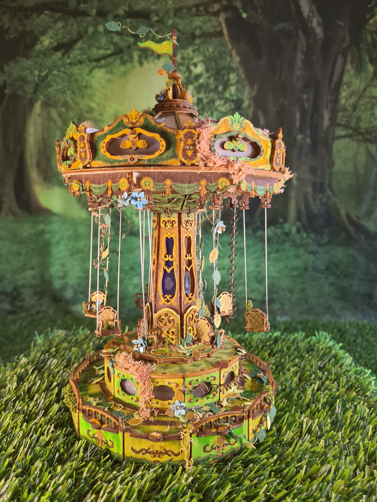 Robotime glowing carousel model stands in a forest style scene with green moss.