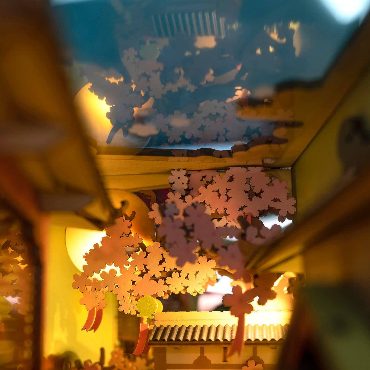 Rolife Falling Sakura book nook ceiling view with laser-cut cherry blossom branches spread across a warm glowing sky panel in pale wood tones